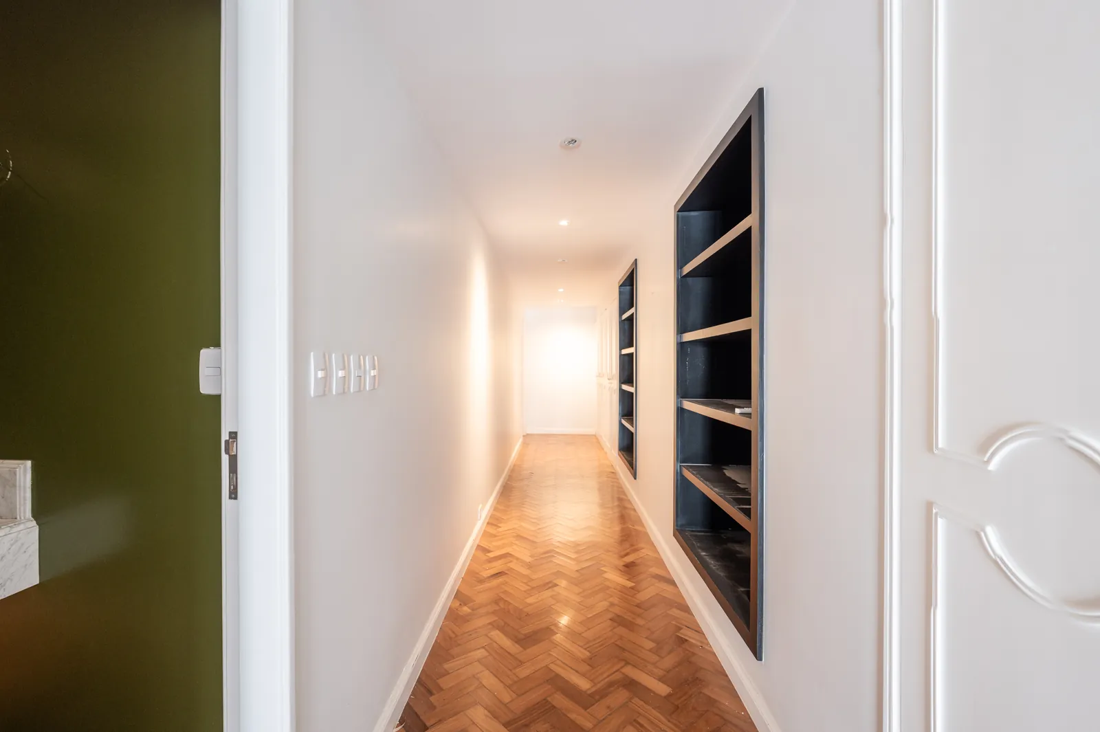 A corridor in herringbone parquet with built-in shelving
