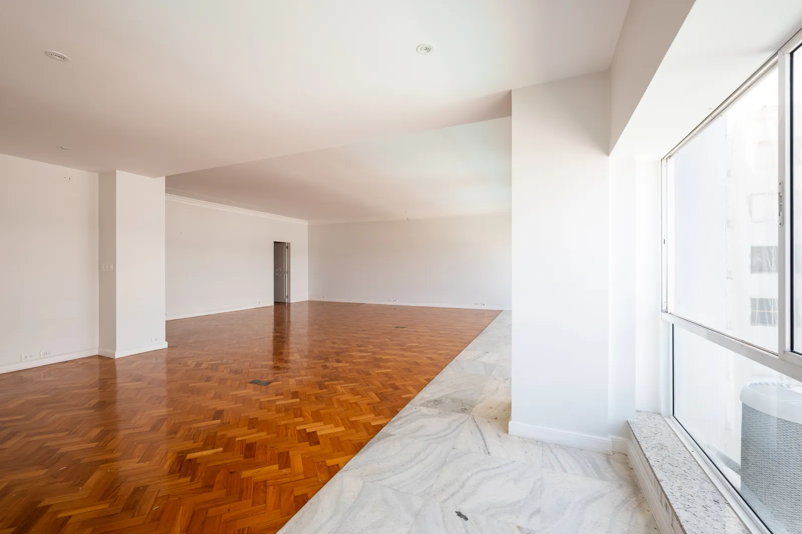 A room with parquet and a marble threshold, light from the windows